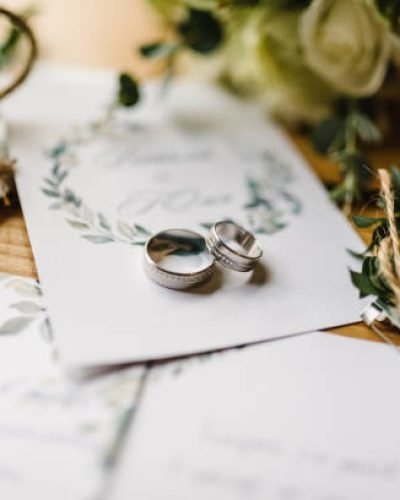 Stylish rings, flowers on wooden table background. Letters from the bride and groom. Vows. Engagement. Luxury marriage and wedding accessory concept.